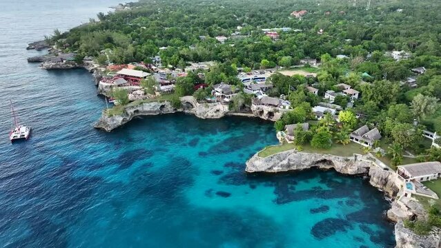 flight along stunning rocky cliffs landscape in West End, Negril, Jamaica, aerial landscape view of area around the famous Rick's Cafe in Negril, with boats near the cliff jumping spot - video footage