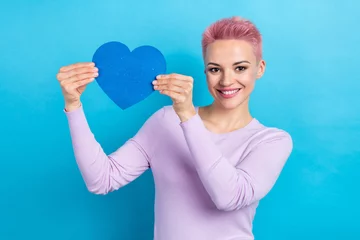 Fotobehang Portrait of good mood funny woman pink hairdo wear stylish sweatshirt demonstrate large paper heart isolated on blue color background © deagreez