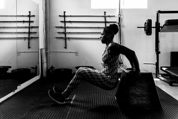 Fitness-focused woman is performing a strength-training exercise, performing dips in a gym