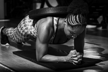 Athletic female fitness enthusiast engaging in a weighted planking exercise, demonstrating strength
