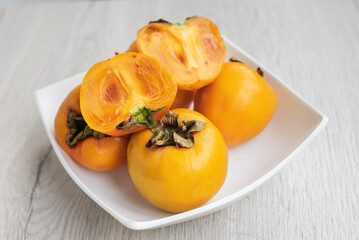 Fresh orange persimmon on a white dish.