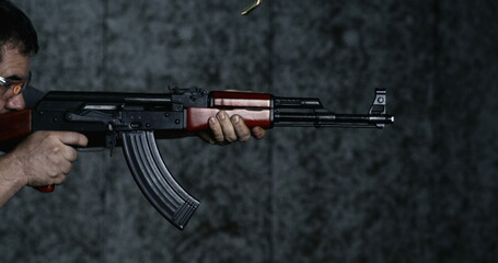 Side view of person shooting an AK-47 Rifle in high-speed 800 fps. Slow-motion of man aiming and...