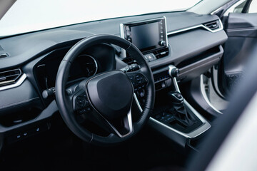 Modern black car interior, leather steering wheel, climate control, navigation, air ducts,...