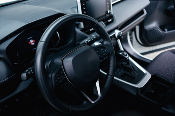 Fototapeta na wymiar Modern black car interior, leather steering wheel, climate control, navigation, air ducts, deflectors on the car panel. Details interior. 