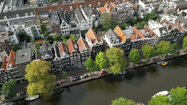 Magical summer view of the city with picturesque canal with boats, striking terraced houses and nearby streets with parked cars from the birds-eye view. High quality 4k footage