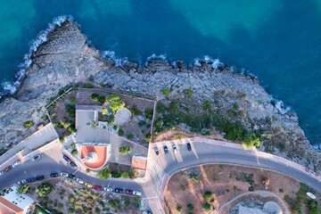 Aerial view above of a small lighthouse by the rocky coastline in Oropesa, Spain. - Powered by Adobe