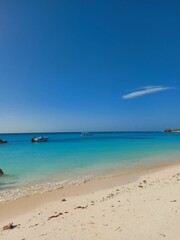 Fototapeta na wymiar Beach scene with an idyllic island with several boats in the background in Tanzania, Zanzibar