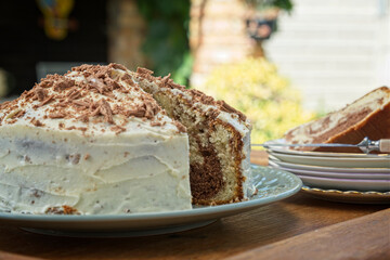 Iced marble cake with chocolate flakes on a wooden tray outdoors