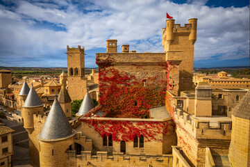 View of the Olite castle and palace in Navarra, Spain, with its slender towers and the red vine...