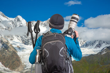 male tourist photographer with a backpack looks at the beauty of nature in the mountains. nature hikes in the mountains