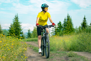 Naklejka premium Beautiful woman cyclist rides a bicycle in nature. Healthy lifestyle and sports. Leisure and hobbies