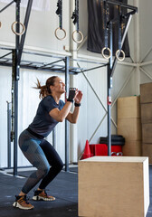 Fototapeta na wymiar Fitness woman doing box jump workout at cross fit gym