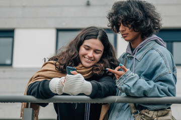 teenage couple on the street looking at mobile phone