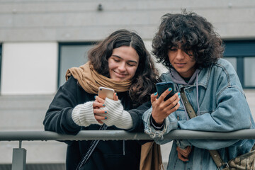 happy teenagers on the street looking at mobile phone - obrazy, fototapety, plakaty