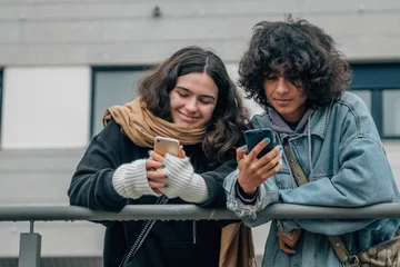 Fotobehang happy teenagers on the street looking at mobile phone © tetxu