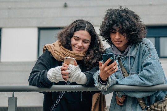happy teenagers on the street looking at mobile phone