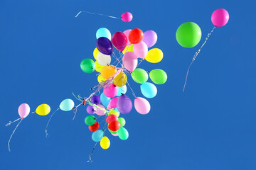 many multicolored balloons flying in the blue sky. Holiday accessories and decorations