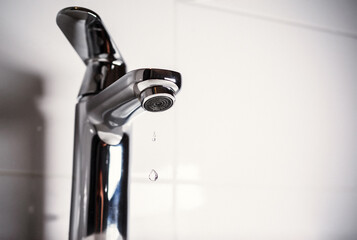 Clean water is dripping from the faucet in the sink. Water leaking and saving. Selective focus.
