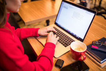 Woman skilled copywriting of homepage working on laptop computer while sitting in coffee shop...
