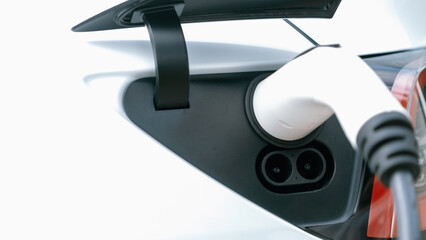 Closeup EV charger plug handle attached to electric vehicle port, recharging battery from charging...