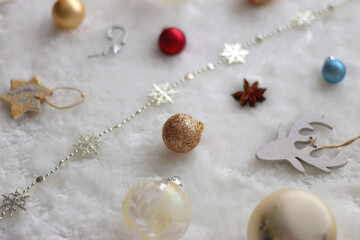 Various colorful Christmas oranments and white faux fur blanket. Selective focus.