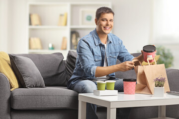 Young man sitting on a sofa with takeaway food boxes