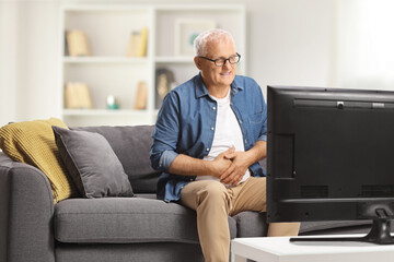 Mature man with abdominal pain sitting on a sofa