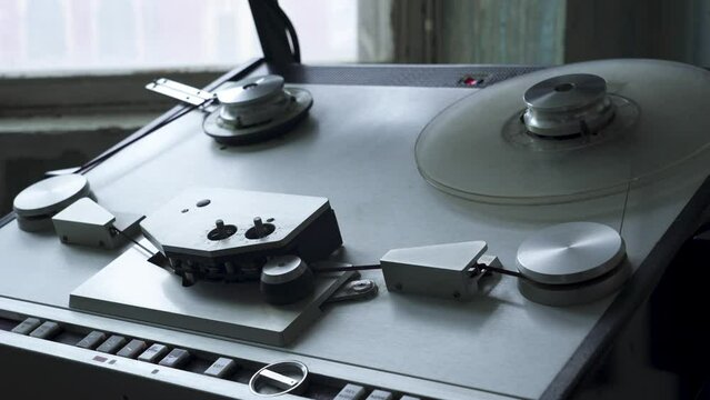Old tape recorder. Audio reel player. Vintage recorder roller rewinds tape. Tape recorder is playing