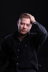 Obraz premium Strict and stylish Man in black shirt on dark background.