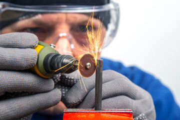 Man mechanic processes metal with an engraving drill. Locksmith industry. Metal cutting processing