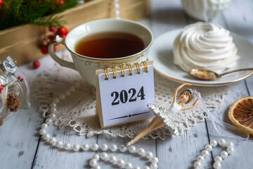 A cup of tea, New Year's toys, a calendar for the New Year 2024. Still life in vintage style.