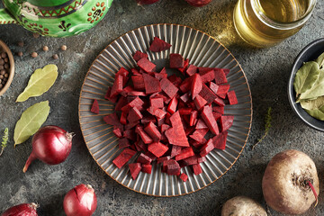 Sliced red beet on a black plate with onions and spices - obrazy, fototapety, plakaty
