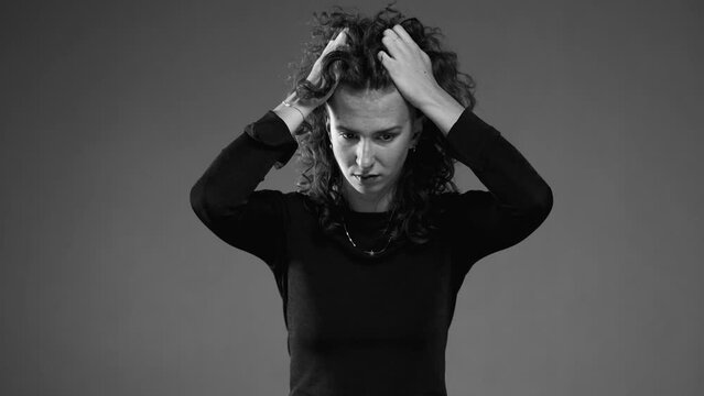 Dramatic desperate scene of woman pulling hair in black and white. Person feeling dread and preoccupation