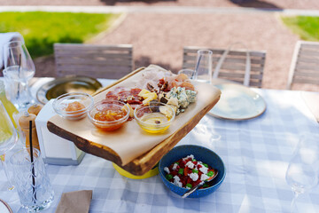 Wooden tray with assorted meats and cheeses with sauces.