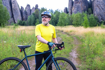 bearded man cyclist in yellow clothes is resting on a bicycle on the road in nature. sports,...