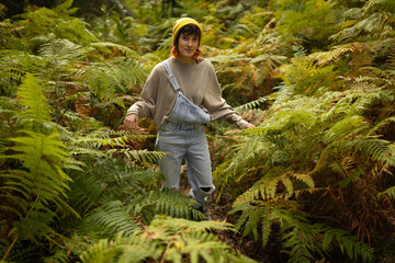 woman in a fern forest walking with a happy woolen cap