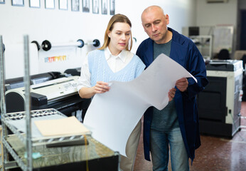 Service engineer and office worker checking printed document together against color chart