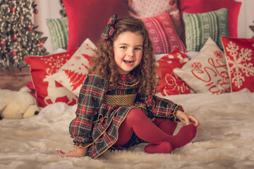 Little girl sitting on a carpet smiling at Christmas