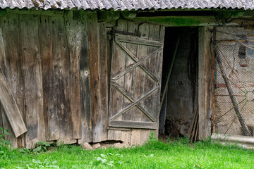 Vintage broken wooden barn door made from boards.