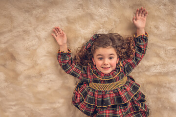 Girl lying on a carpet with her arms upwards at Christmas time