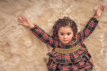 Girl lying on a carpet with her arms upwards at Christmas time