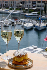 Drinking of French brut champagne sparkling wine with cake Tarte Tropezienne, club party in yacht harbour of Port Grimaud near Saint-Tropez, French Riviera vacation, France