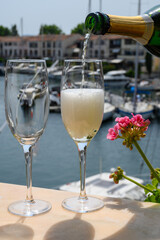 Drinking of French brut champagne sparkling wine in glasses, club party in yacht harbour of Port Grimaud near Saint-Tropez, French Riviera vacation, France