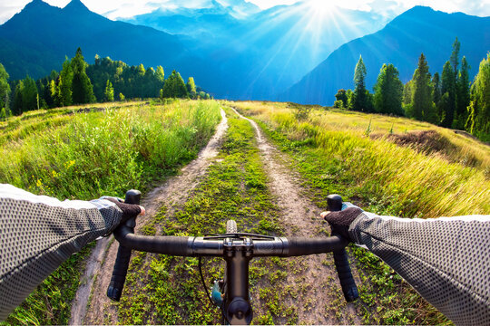 hands on the handlebars of a bicycle of a cyclist riding along a trail in nature. Point of view
