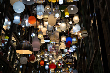 Fototapeta na wymiar Many different ceiling lamps with lightbulbs in dark room with mirrors