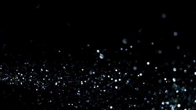 4K Multicolored abstract glitter particles. Shimmering Particles Falling glitter with glare on a bokeh background. Titles in awards, music, wedding, anniversary, party, and presentation backdrops.