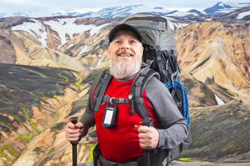 happy bearded man traveler with hiking equipment against the backdrop of a mountain landscape. travel, hiking and adventure