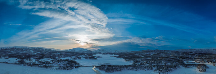 Scenic aerial Sunset panorama on frozen lake, mountains with snow mobile traces, northern green lights over mountains. Scandinavian night winter landscape, Norway, Sweden
