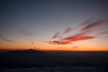 Majestic scene of winter mountains surrounded by fog and bright clouds during twilight