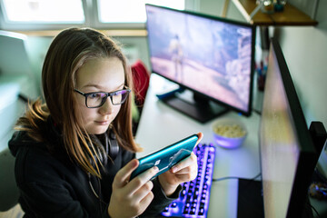 Young gamer girl playing mobile phone games at home